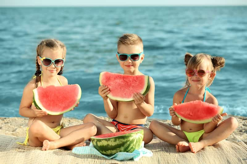 Enfants mangent de la pastèque à la plage